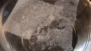 Ein Mother’s Earth Spülmaschinenblatt beim Auflösen für nachhaltiges Spülen mit einem plastikfreien Spülmittel im Wasser.